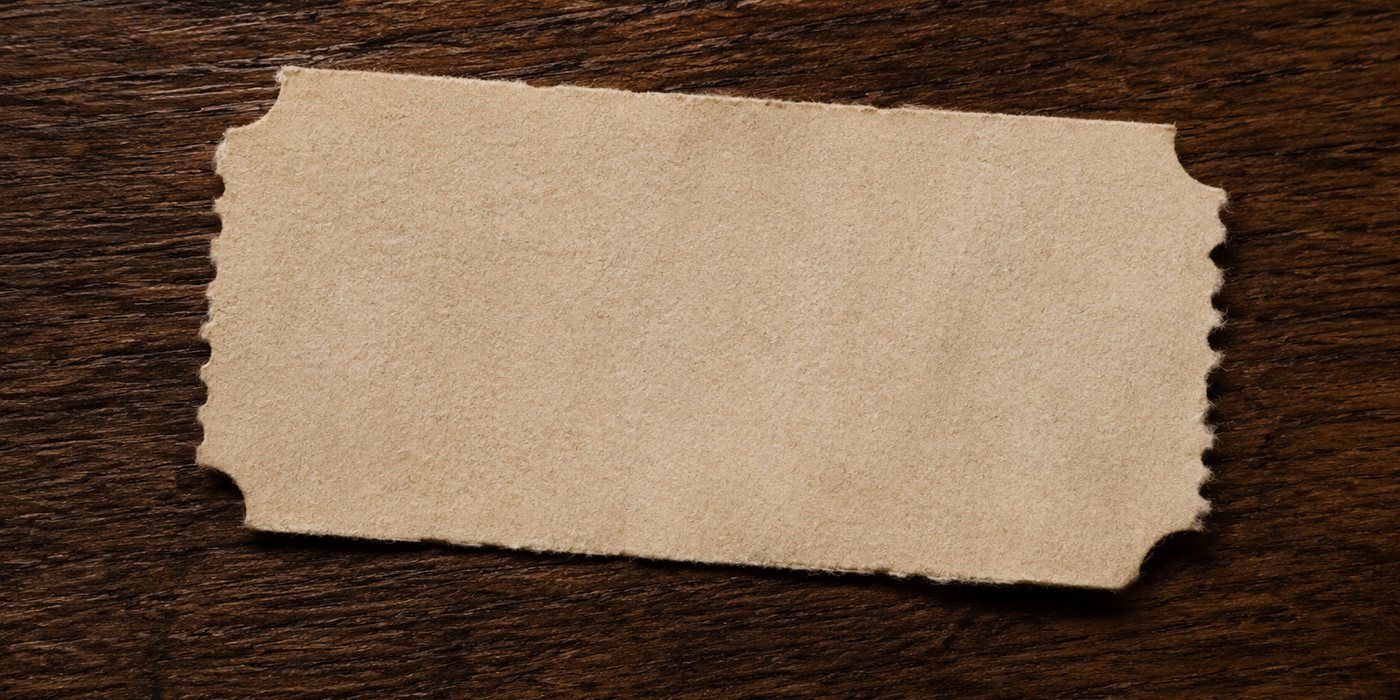 Serpihan tiket kertas koyak kosong di kayu gelap, tiada teks